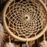 Atrapasueños artesanal tejido con fibras naturales y plumas, sobre un fondo de madera rústica con luz solar suave.