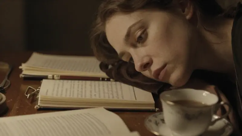 Mujer pensativa en un estudio tenuemente iluminado, con diarios de sueños y una taza de café, evocando una atmósfera de introspección y análisis.