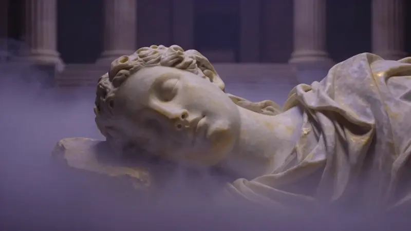 Cabeza de mármol de Hipnos, dios del sueño, emergiendo entre niebla dorada y lavanda con ruinas de un templo griego al fondo.