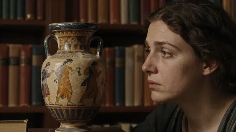 Mujer observando un jarrón griego antiguo con una escena onírica, en un estudio lleno de libros con iluminación tenue y ambiente académico.