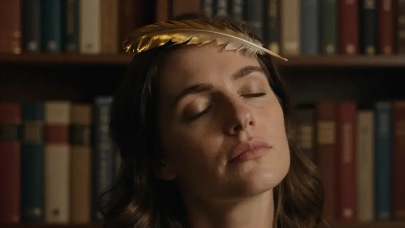 Mujer con los ojos cerrados en un estudio lleno de libros, con una pluma de águila sobre su frente, en una atmósfera de introspección y calma.