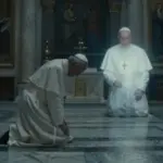Cámara papal tenuemente iluminada con una figura arrodillada en oración, y la silueta desvaneciéndose del Papa Francisco proyectada sutilmente en la luz.