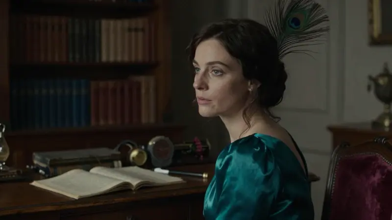 Retrato onírico de una mujer pensativa con una pluma de pavo real en el cabello, sentada en un estudio victoriano con libros de psicología sobre un escritorio antiguo.