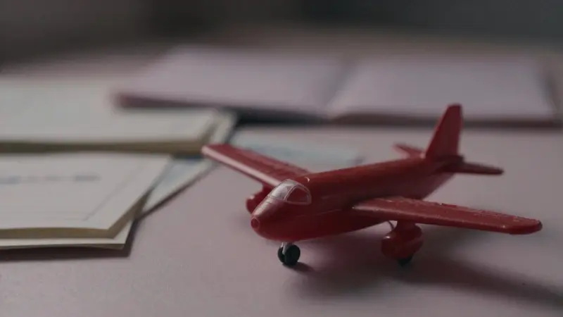 Avión de juguete rojo y desgastado sobre hojas de un diario de sueños, con una iluminación tenue y un ambiente nostálgico.