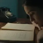 Mujer pensativa en estudio antiguo, rodeada de libros y un teléfono vintage, con iluminación tenue y ambiente melancólico.