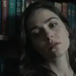 Mujer pensativa en un estudio antiguo con libros y elementos decorativos con forma de tentáculos de pulpo, evocando una atmósfera melancólica y onírica.