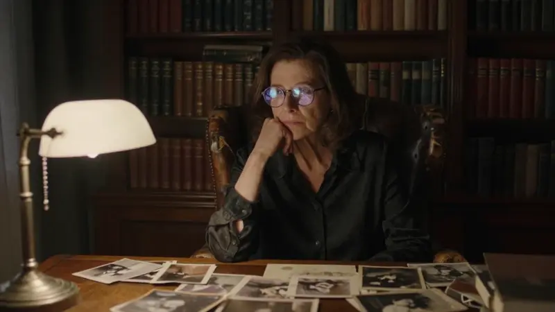 Mujer de mediana edad sentada en un estudio lleno de libros, rodeada de fotografías antiguas y con una expresión pensativa. Un sutil remolino se refleja en sus gafas, creando una atmósfera melancólica y nostálgica.